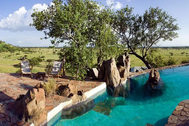 Tented camp veranda overlooking the Serengeti at golden hour, Tanzania safari accommodation.